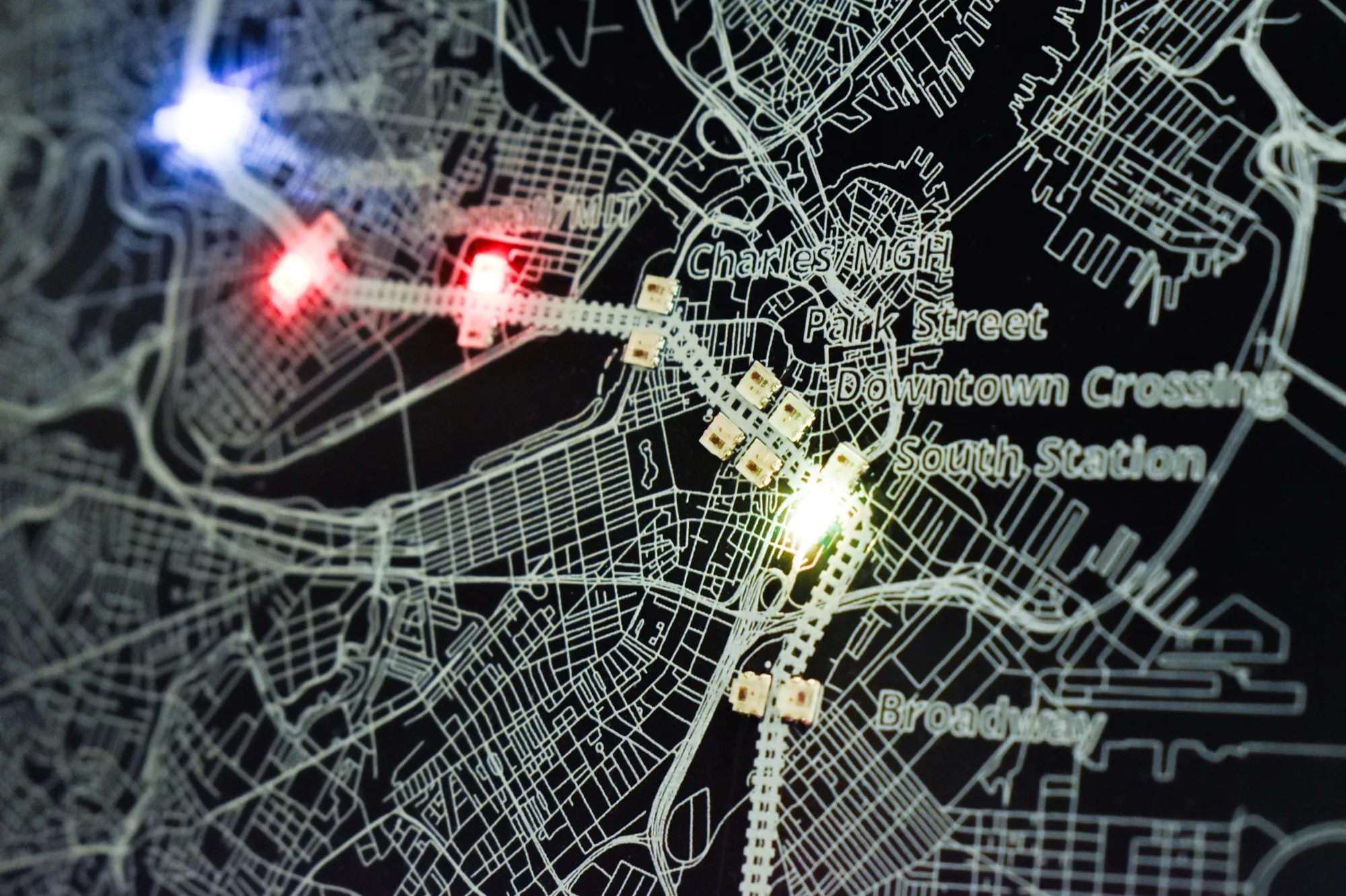 Close-up of WS2812B LEDs illuminated red, blue, and green at stations on a CharlieBoard map.